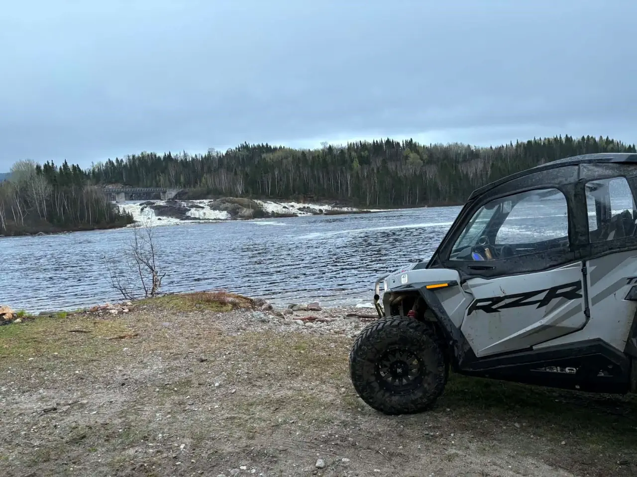 Un côte à côte arrêté au bord de la rivière, devant le barrage et ses rapides.