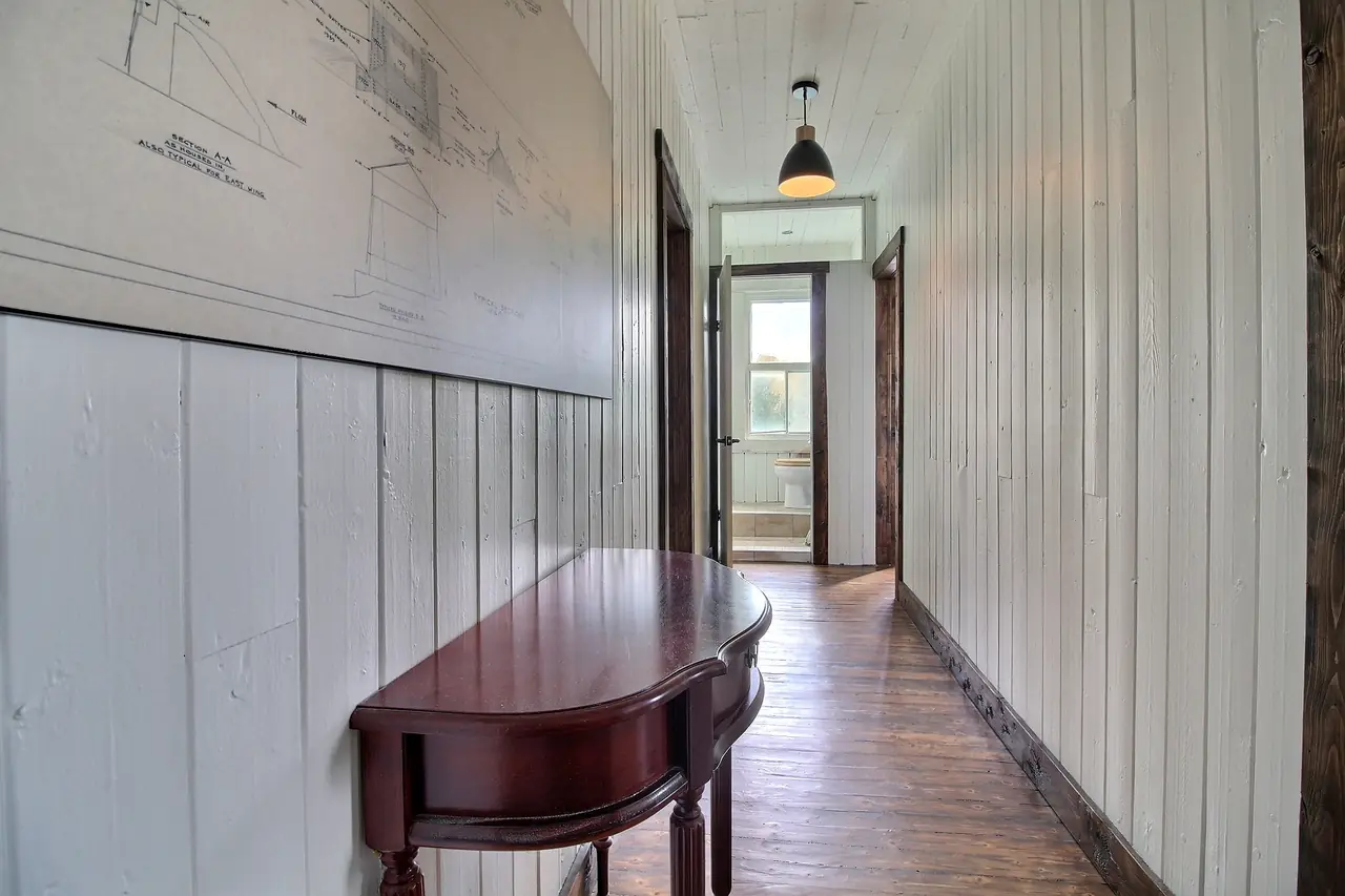 Le passage qui dessert les chambres, boiseries blanches et plancher ancien.